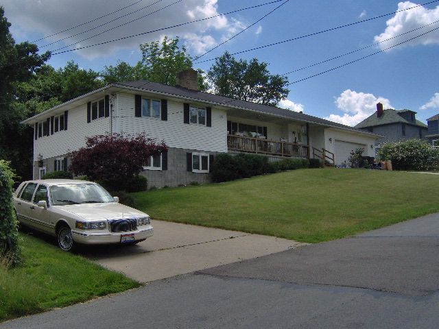 A white car is parked in front of a white house