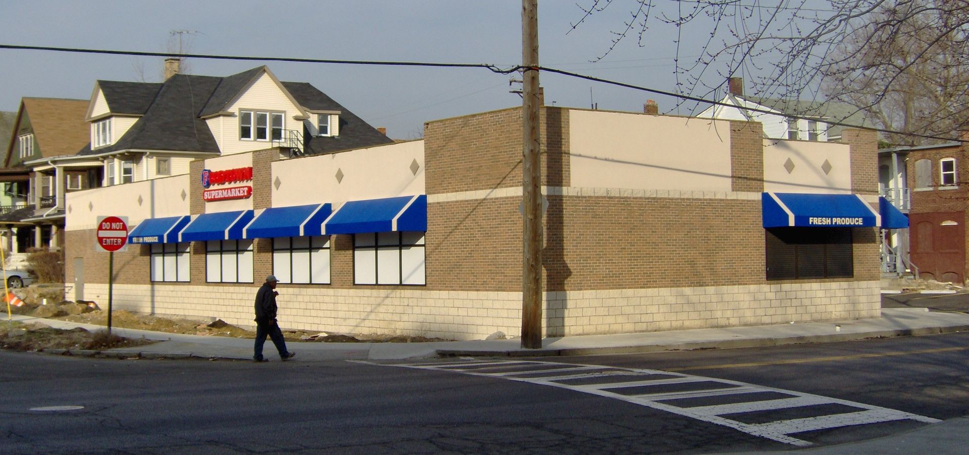 A person is crossing the street in front of a walmart store