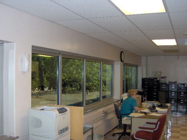 Office with windows overlooking trees, a person working at a desk.