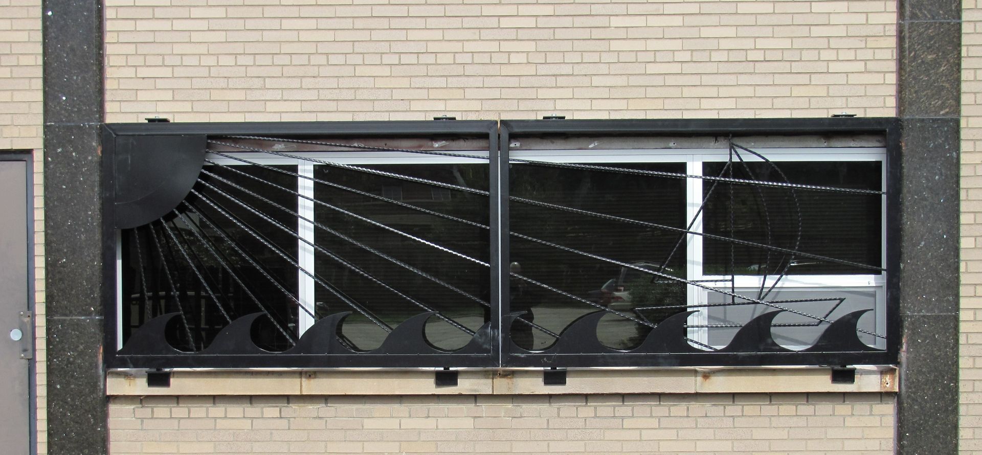 Window with decorative black metalwork depicting a sun, waves, and possibly a boat.
