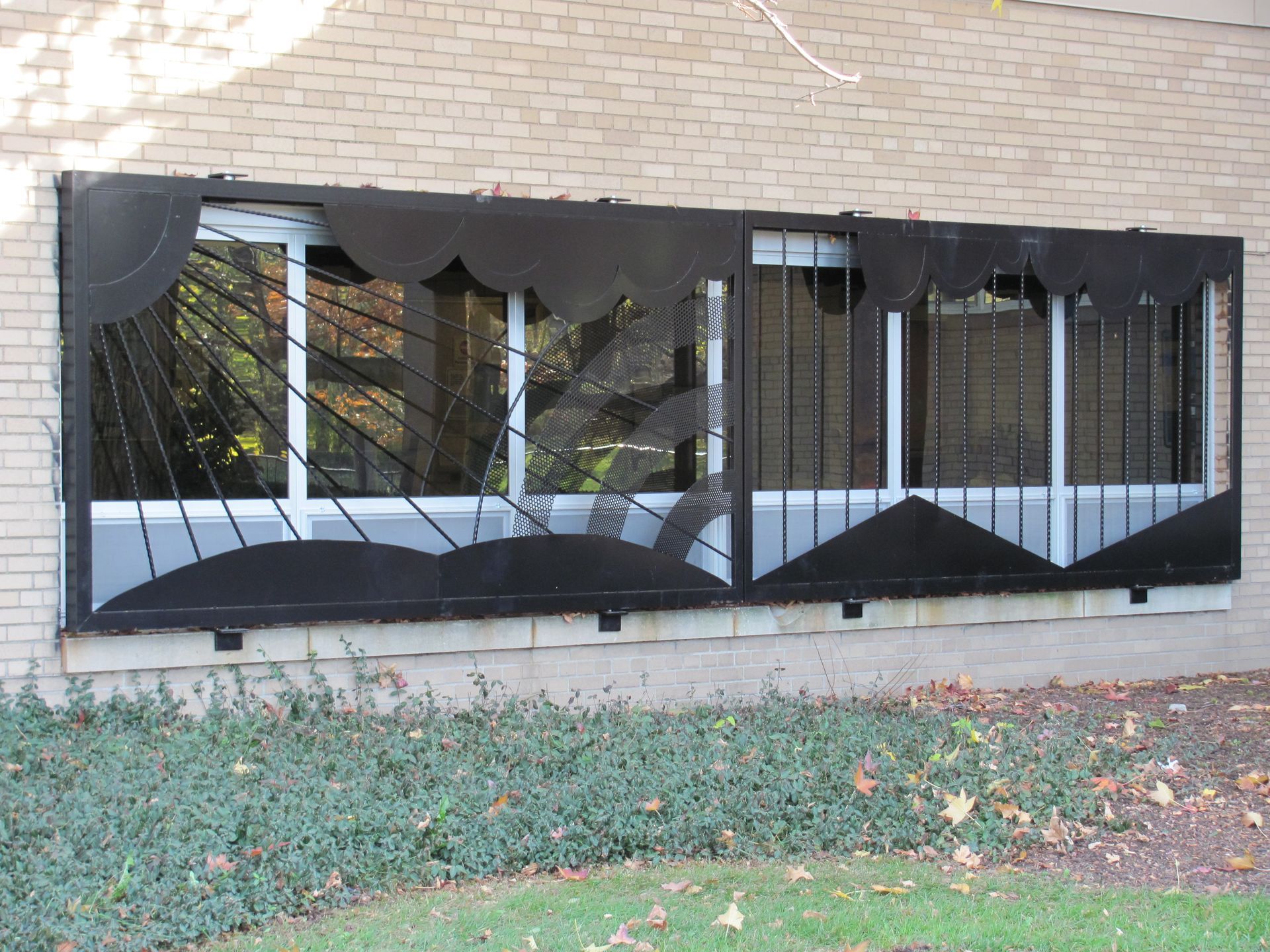 Black metal window security on a building exterior. Decorative sun and cloud motifs.