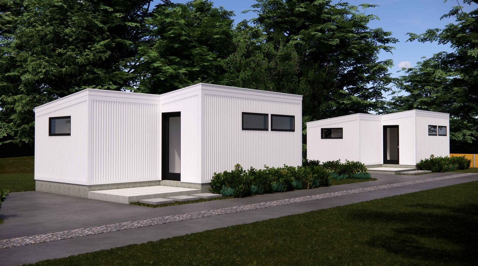 A couple of white houses sitting next to each other on a lush green field.