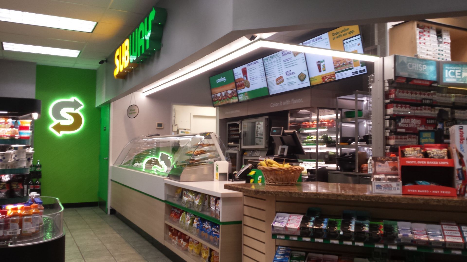 The inside of a subway restaurant with a green sign on the wall.