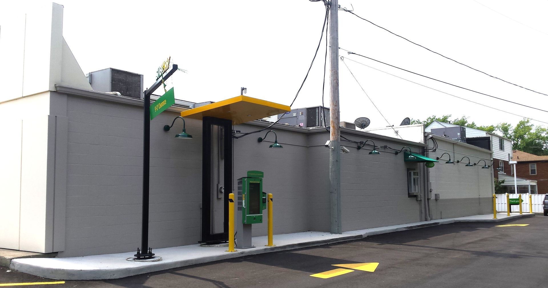 A gray building with a yellow canopy and a green box in front of it.