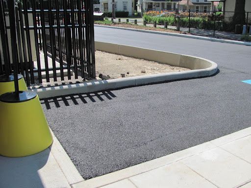 A shadow of a fence is cast on the asphalt