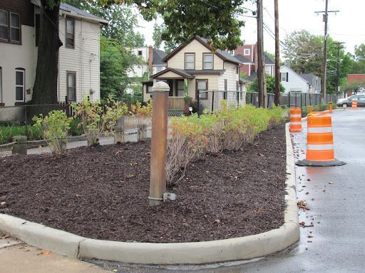 A corner of a street with a concrete curb and orange cones