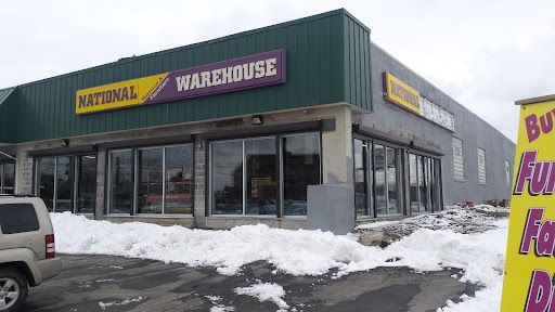 A car is parked in front of a national warehouse building.