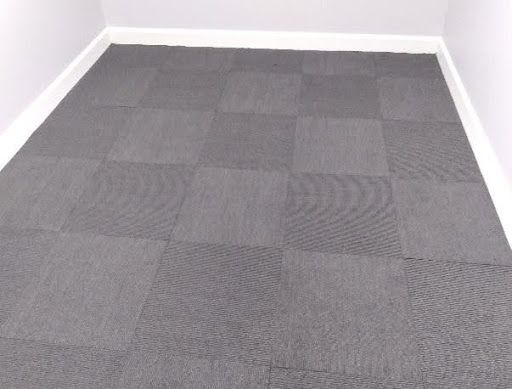 A room with a carpeted floor and a white wall.