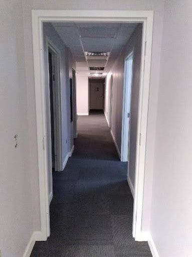 A long hallway with a door open leading to a room.