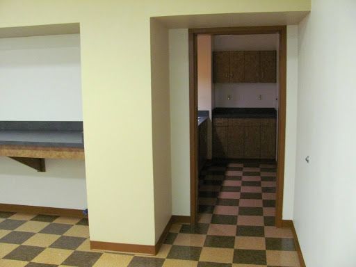 A room with a checkered floor and a door leading to a kitchen