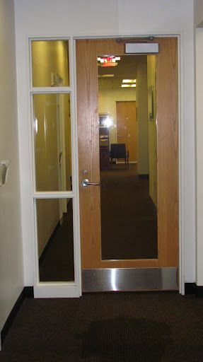 A hallway with a wooden door and a glass door.