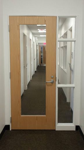 A hallway with a wooden door and a glass door.