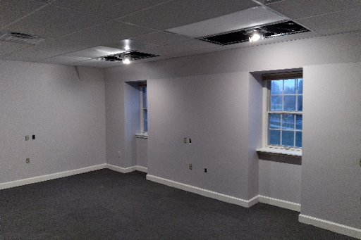An empty room with two windows and a ceiling fan