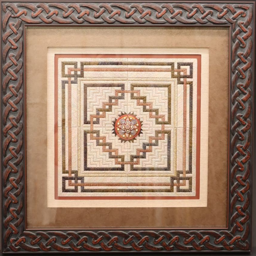 Framed artwork featuring intricate geometric patterns, stepped borders, and a circular medallion in a neutral color palette.