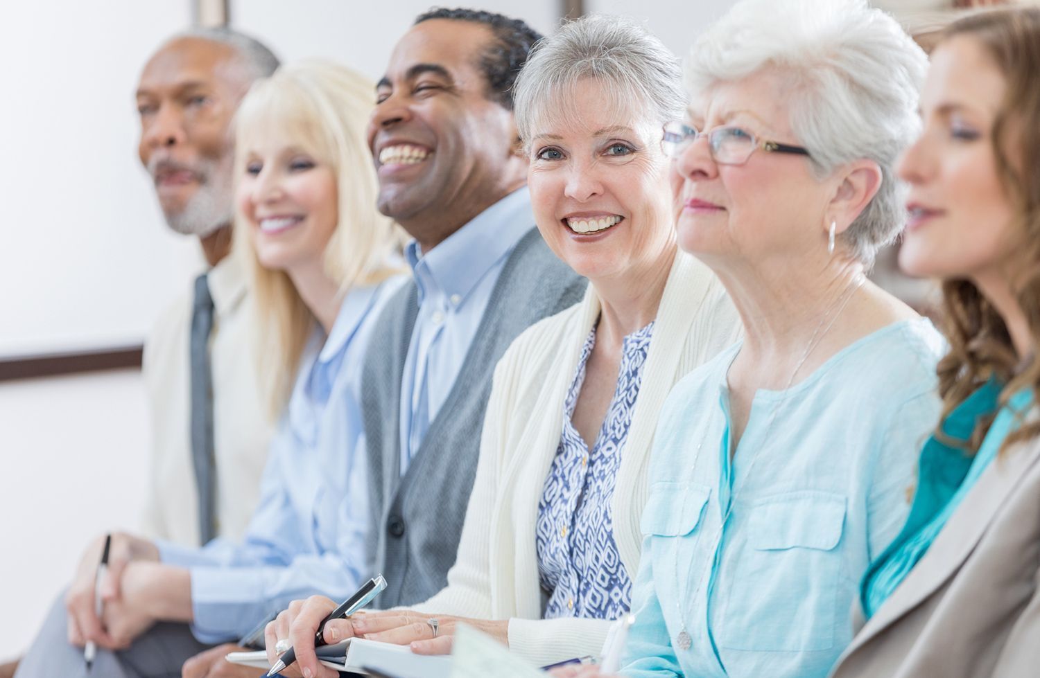 A group of people are sitting in a row and smiling.