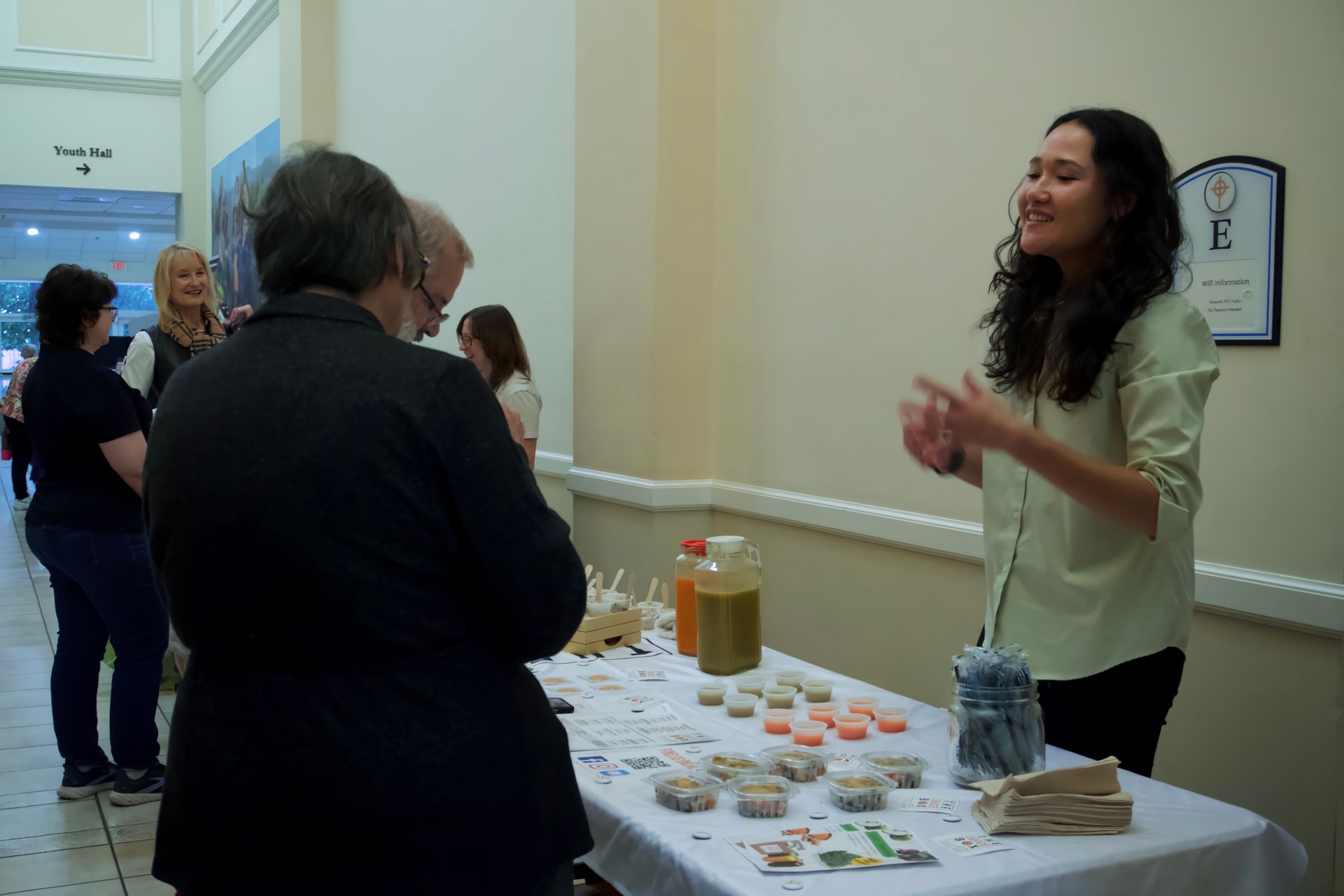 A woman is standing at a table talking to a group of people.