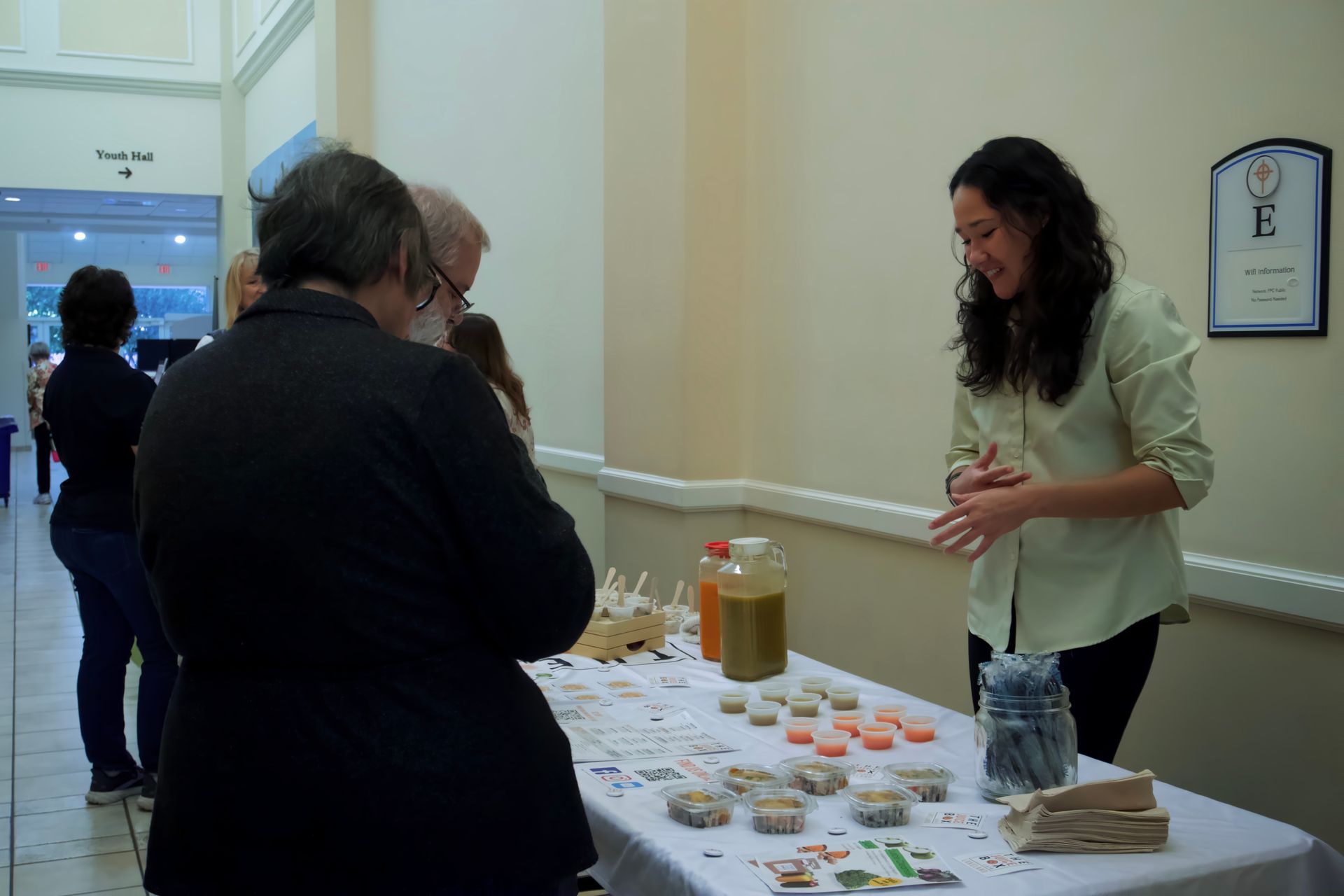 A woman is standing at a table talking to a man