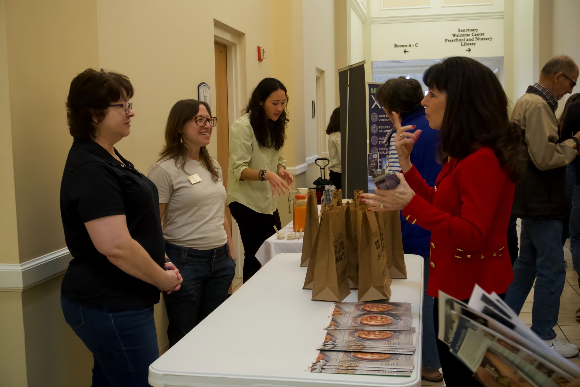 A group of women are standing around a table talking to each other