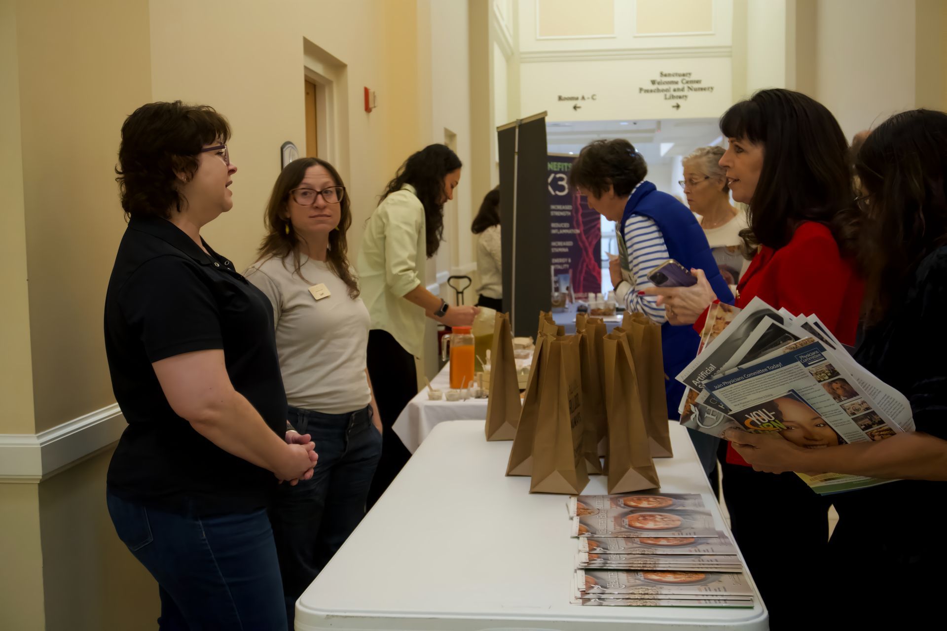 A group of women are standing around a table with magazines on it