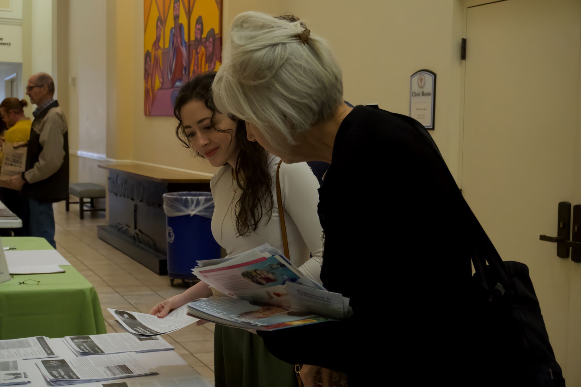 Two women are looking at papers on a table.