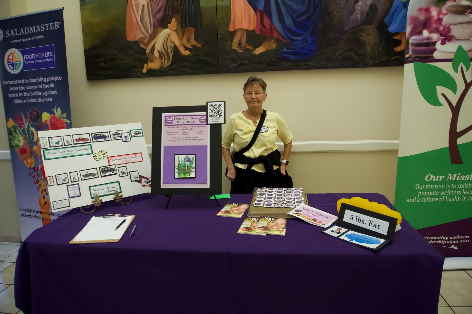 A woman is standing in front of a table with a purple table cloth