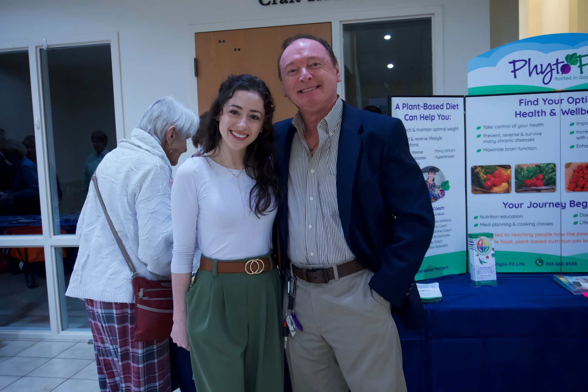 A man and a woman are posing for a picture in front of a table.