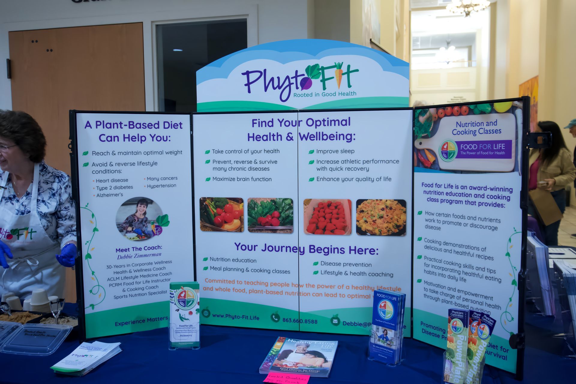A woman stands behind a table with a sign that says phytofit