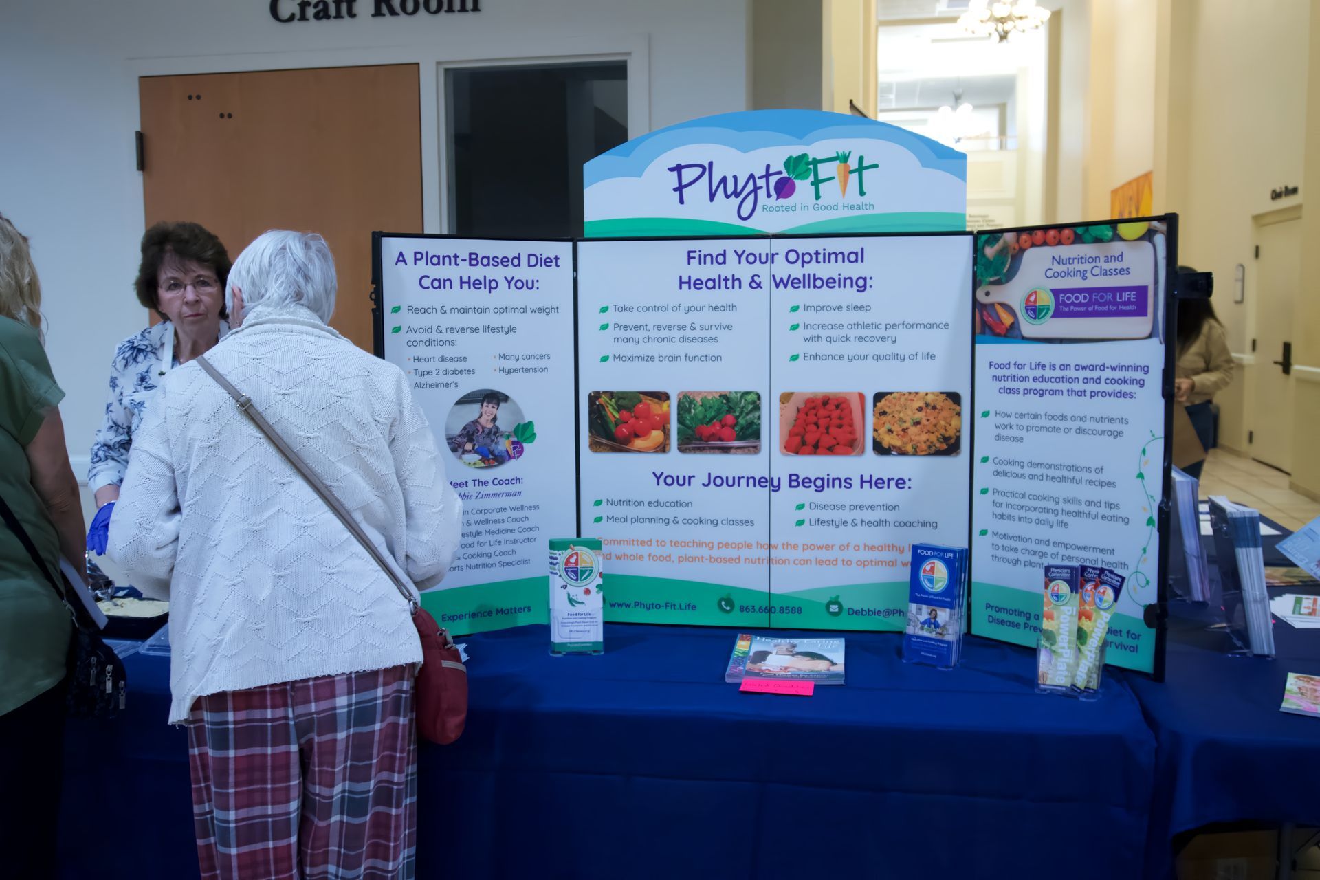 A woman is standing in front of a table with a sign that says plays fit