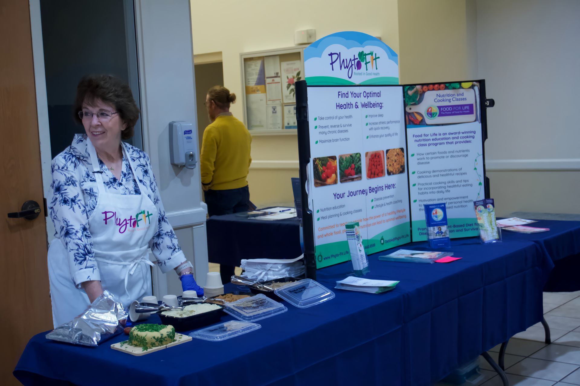 A woman is standing in front of a table with food on it.