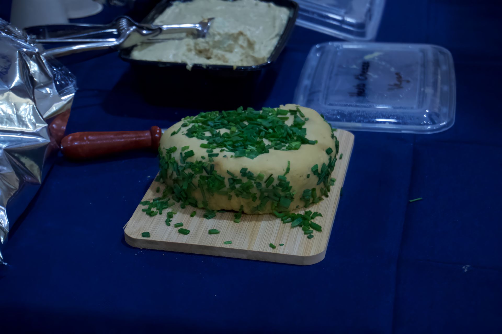 A piece of cheese is sitting on a wooden cutting board on a table.