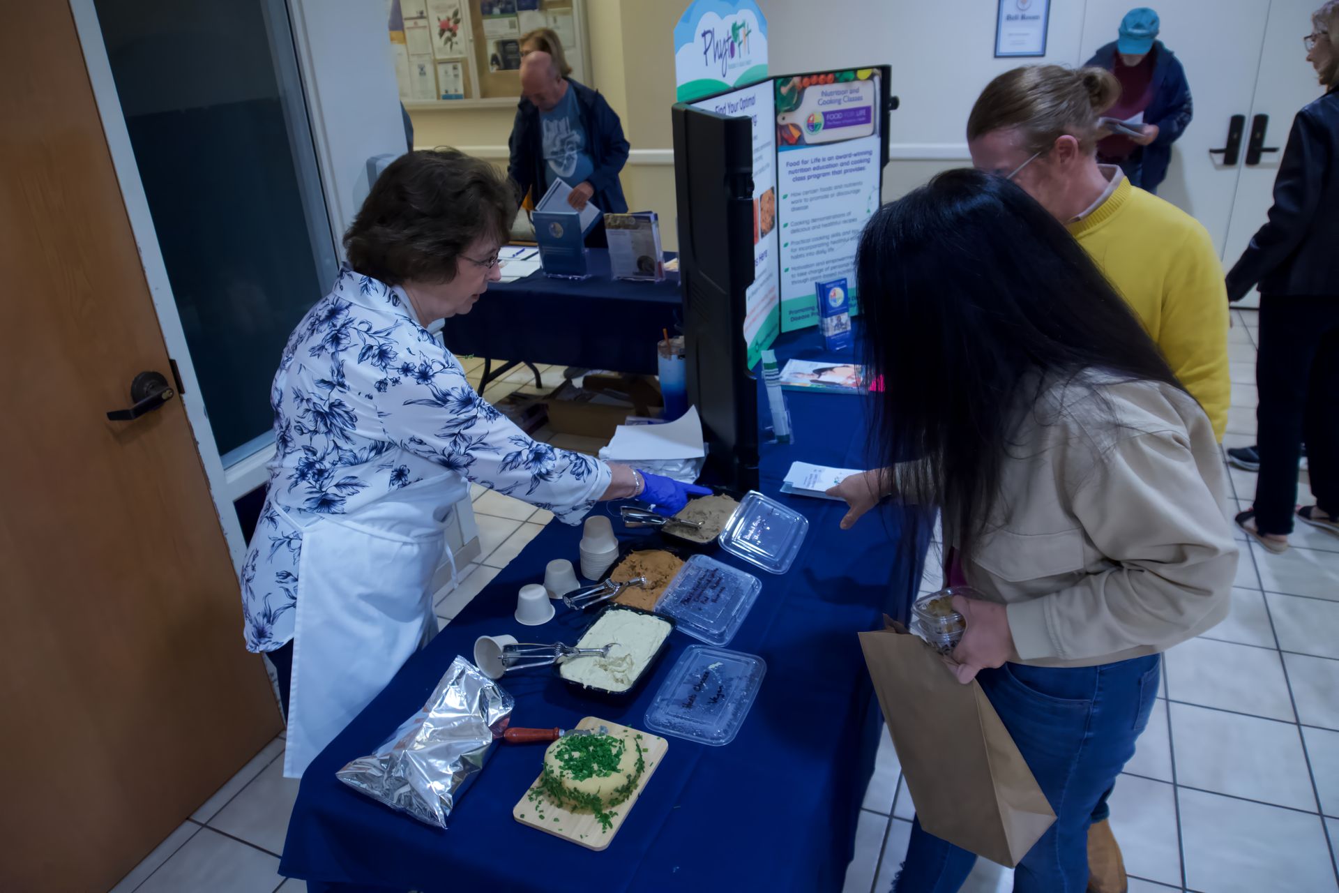 A woman is serving food to a group of people at a table.