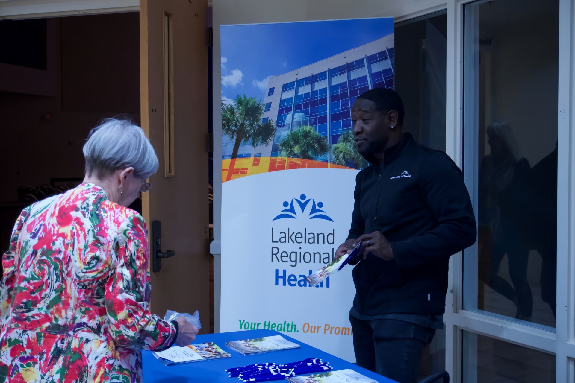 A man and a woman are standing at a table in front of a sign that says lakeland regional health.