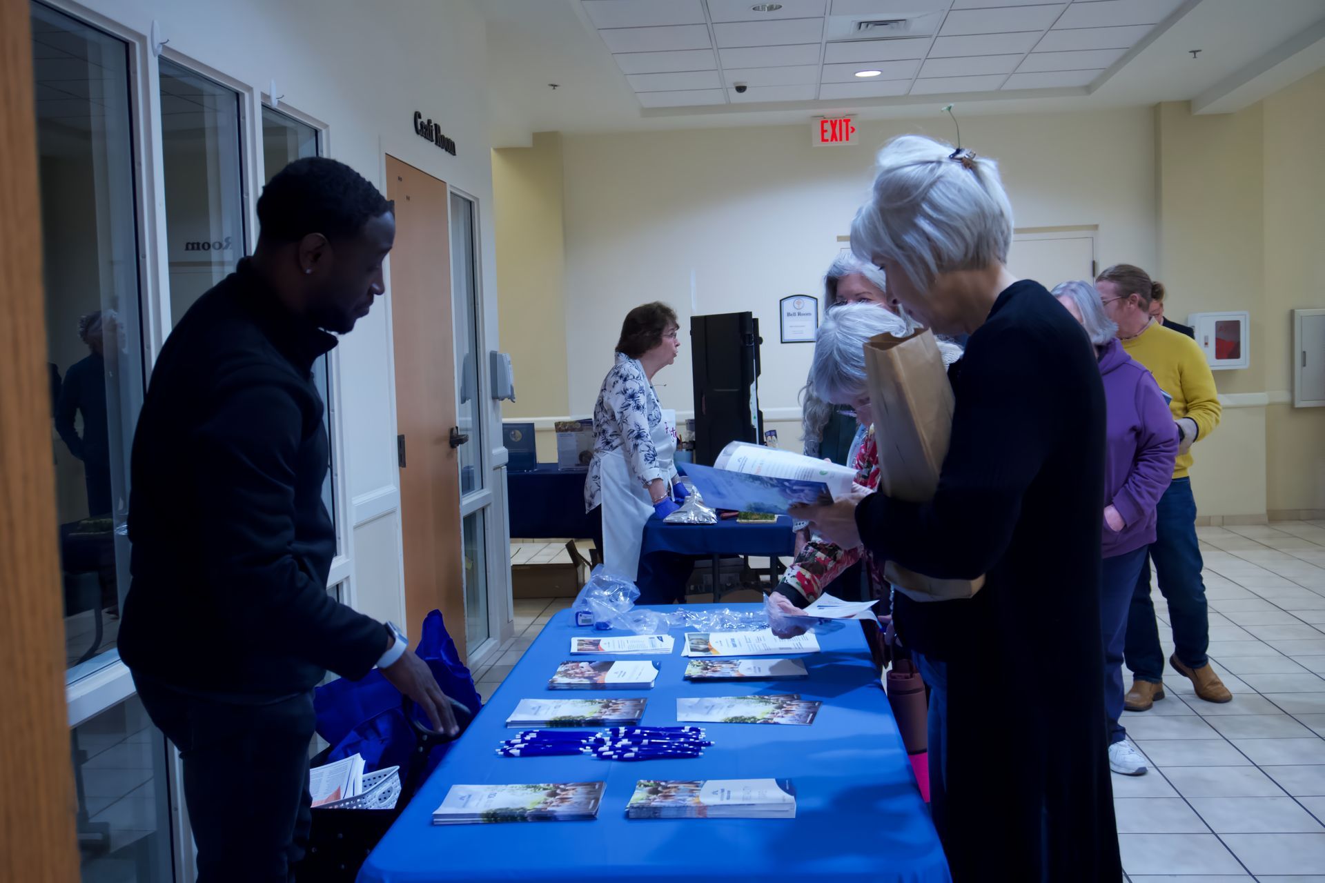 A group of people standing around a table with a blue table cloth