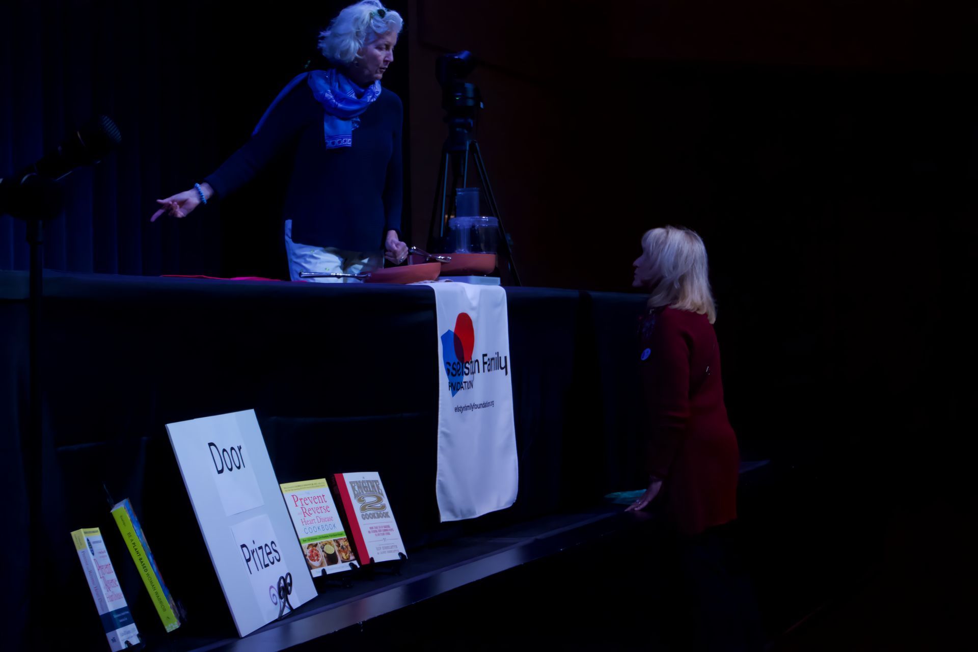 Two women are standing in front of a table with a sign that says ' i love you ' on it