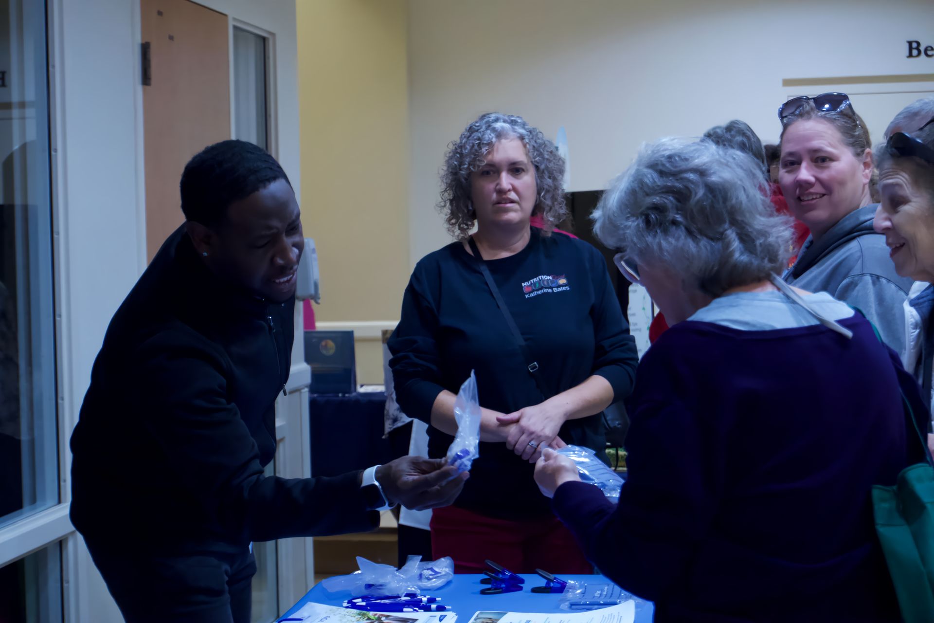 A group of people are standing around a table talking to each other.