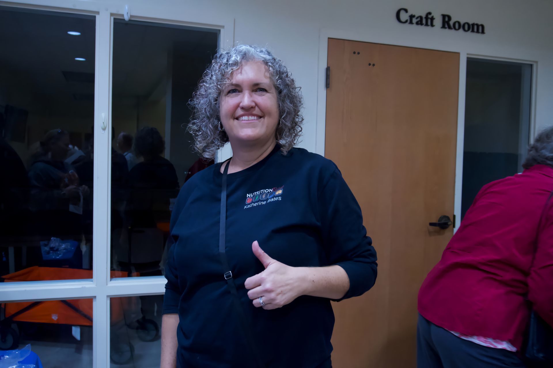 A woman giving a thumbs up in front of a craft room