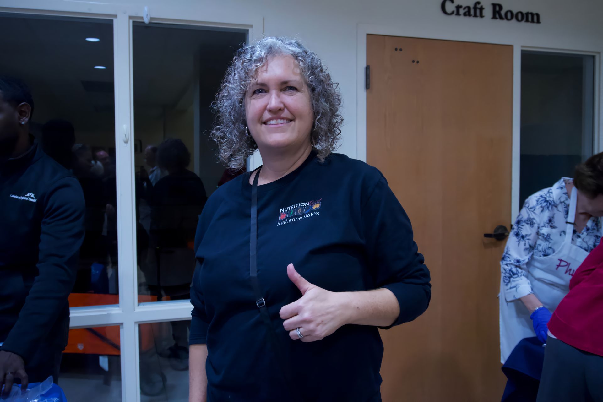A woman is giving a thumbs up in front of a craft room.