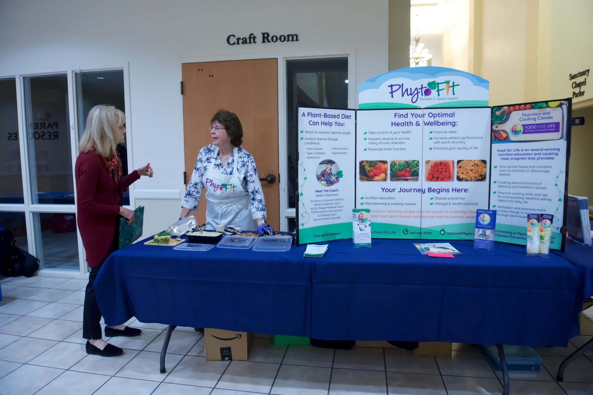 Two women standing at a table with a sign that says plug fit