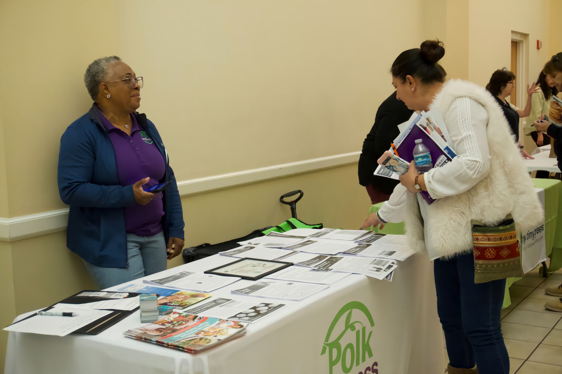 A woman is standing at a table talking to another woman