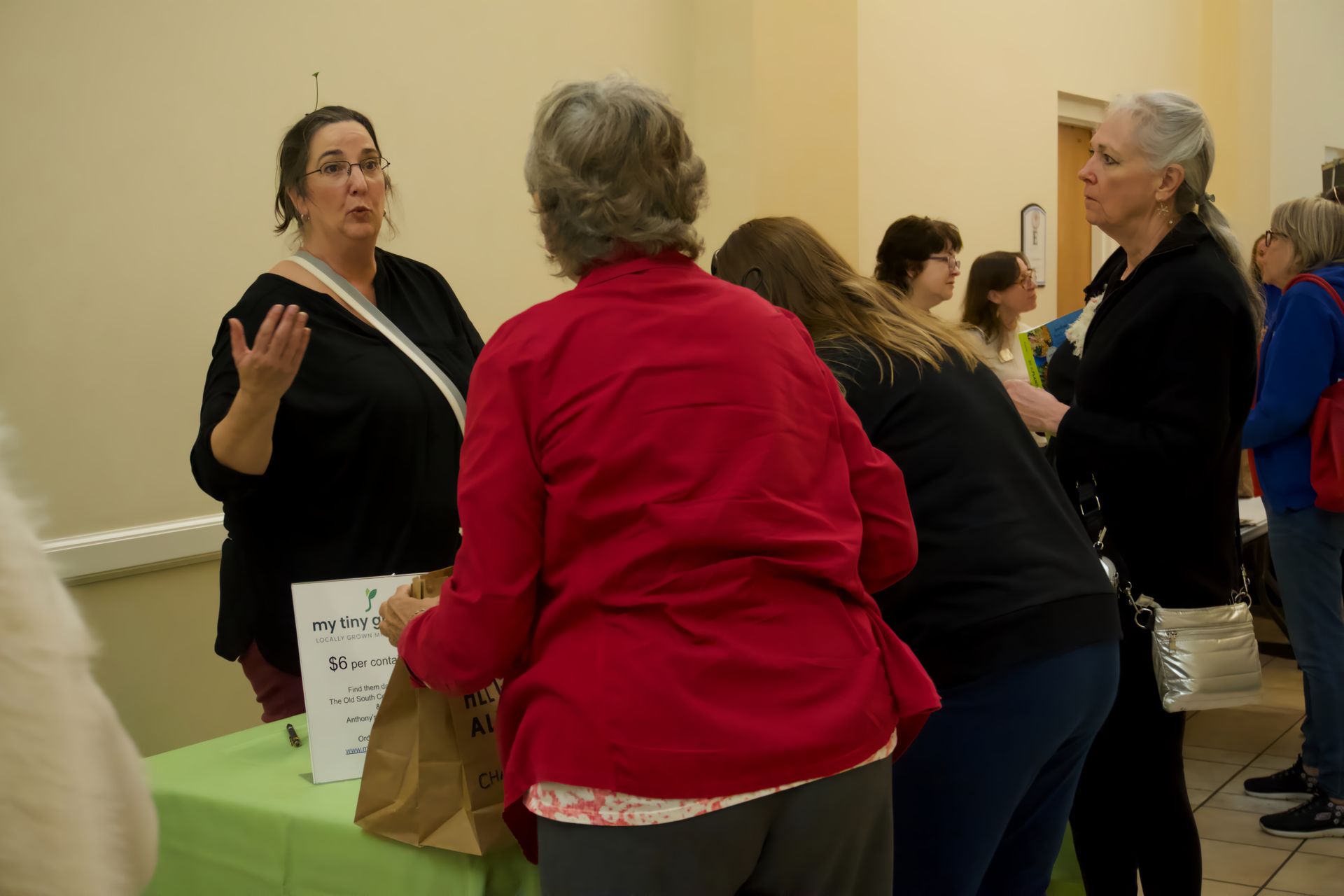 A group of women are standing around a table talking to each other.