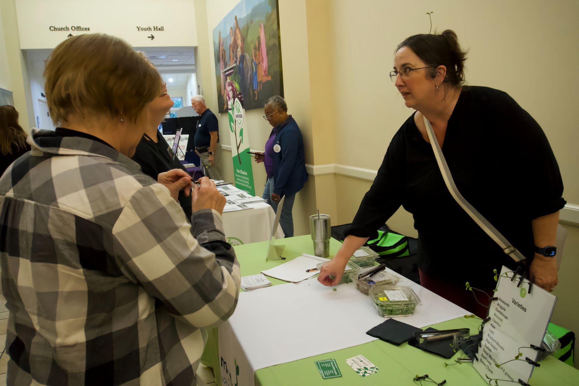 A woman is standing at a table talking to another woman