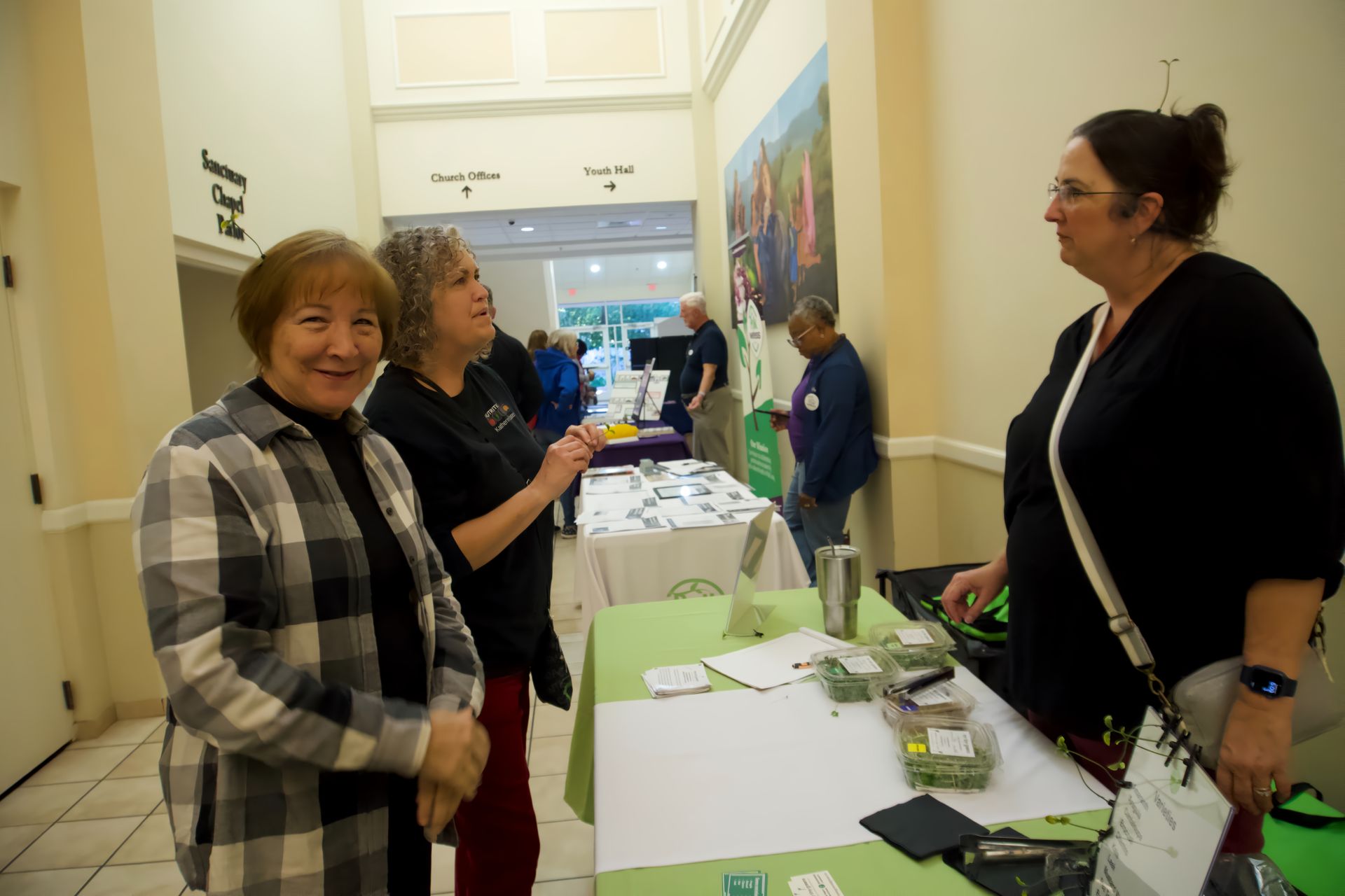 A group of women are standing around a table in a hallway.