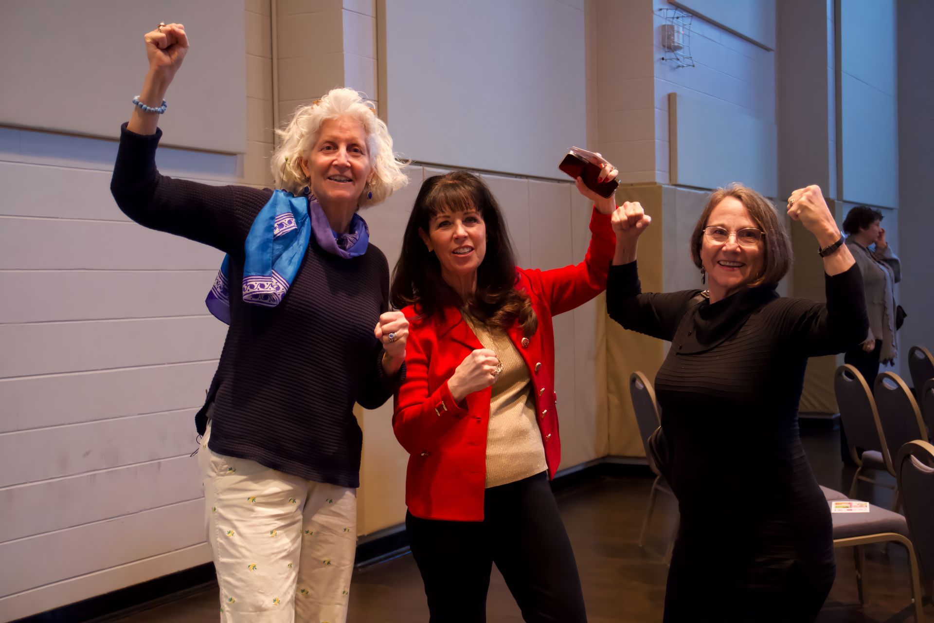 Three women are posing for a picture with their arms in the air.