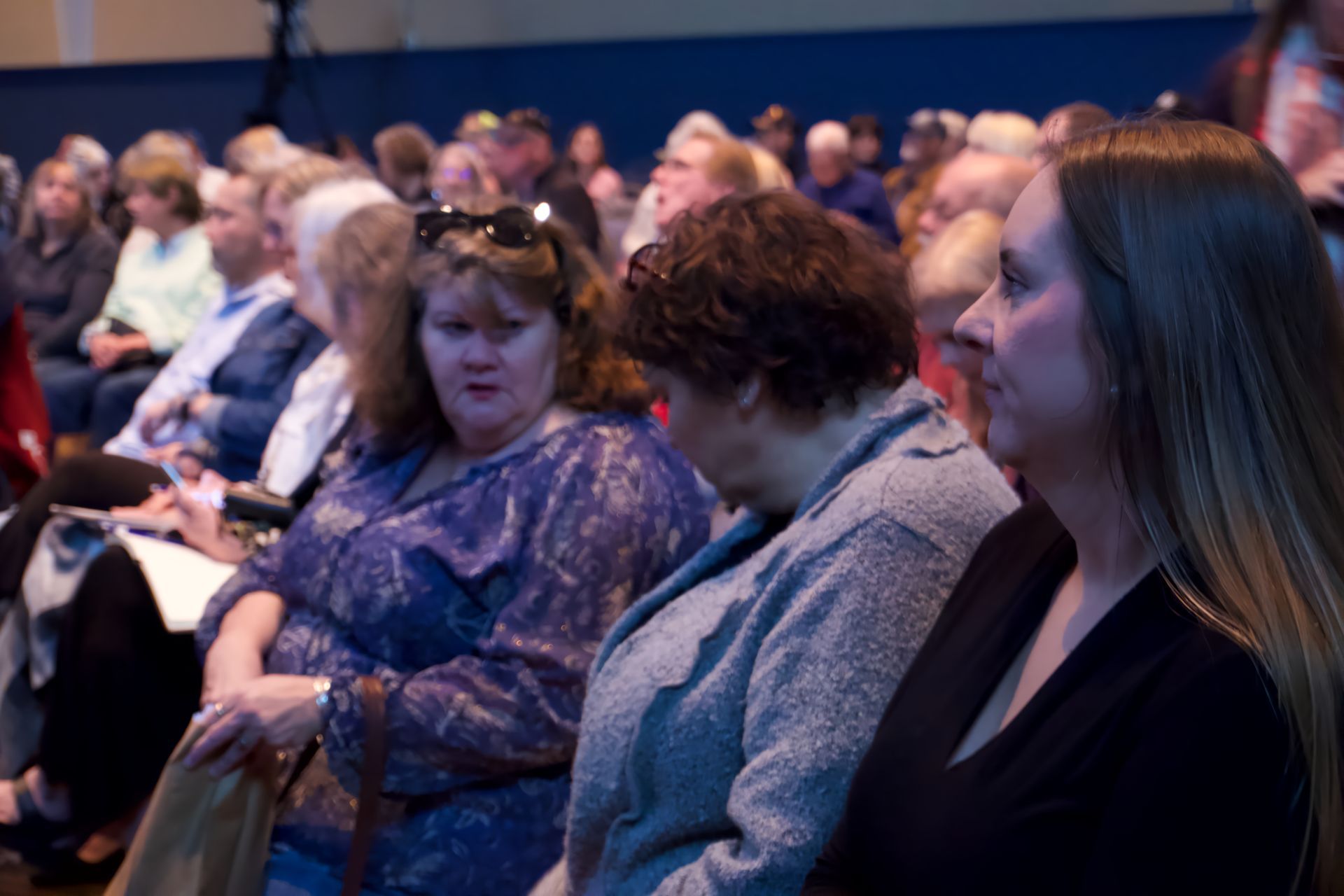A group of women are sitting in an auditorium watching a presentation