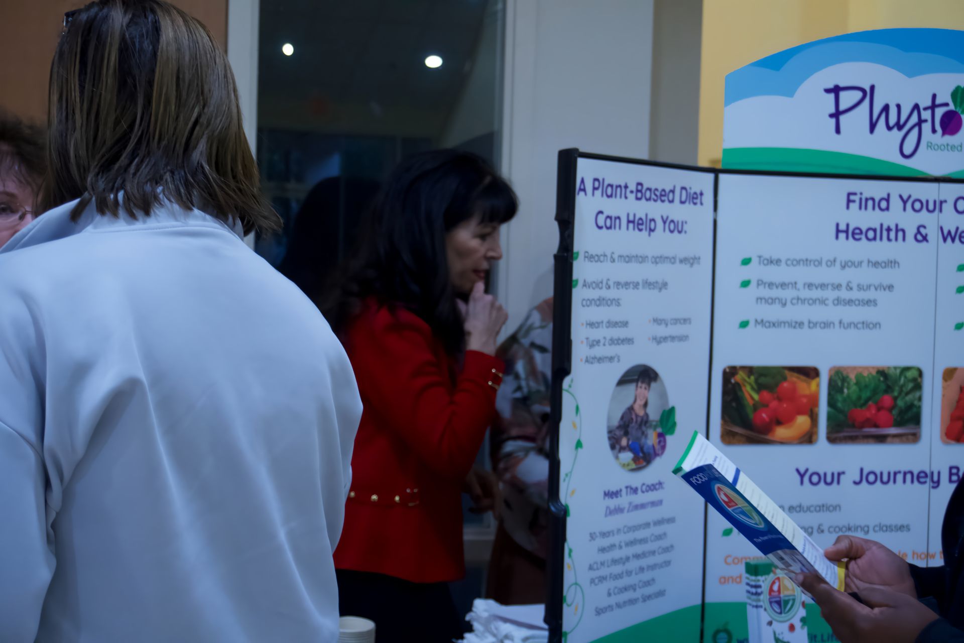 A group of people standing around a table with a sign that says a plant based diet can help you