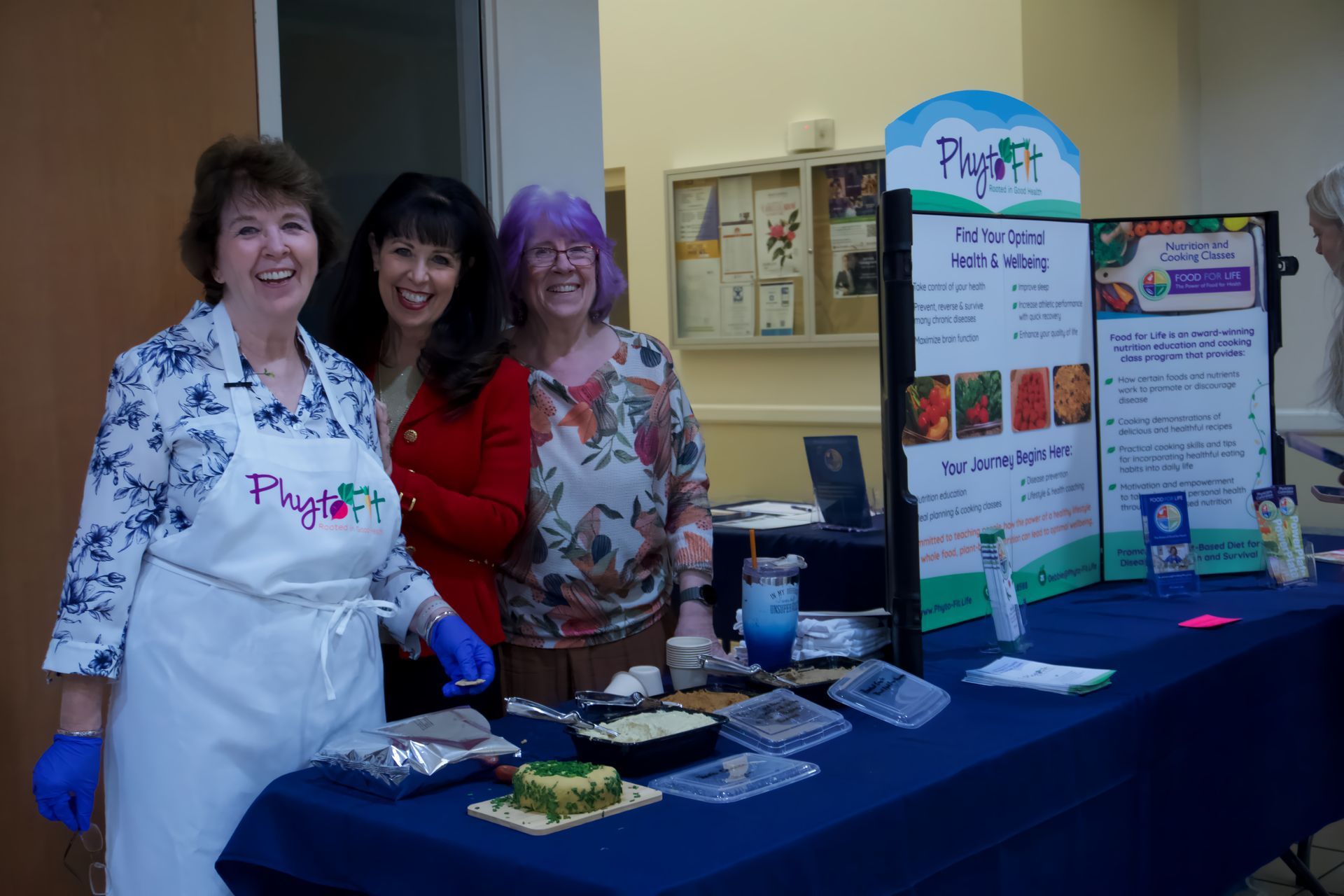 Three women standing in front of a table with a sign that says plant