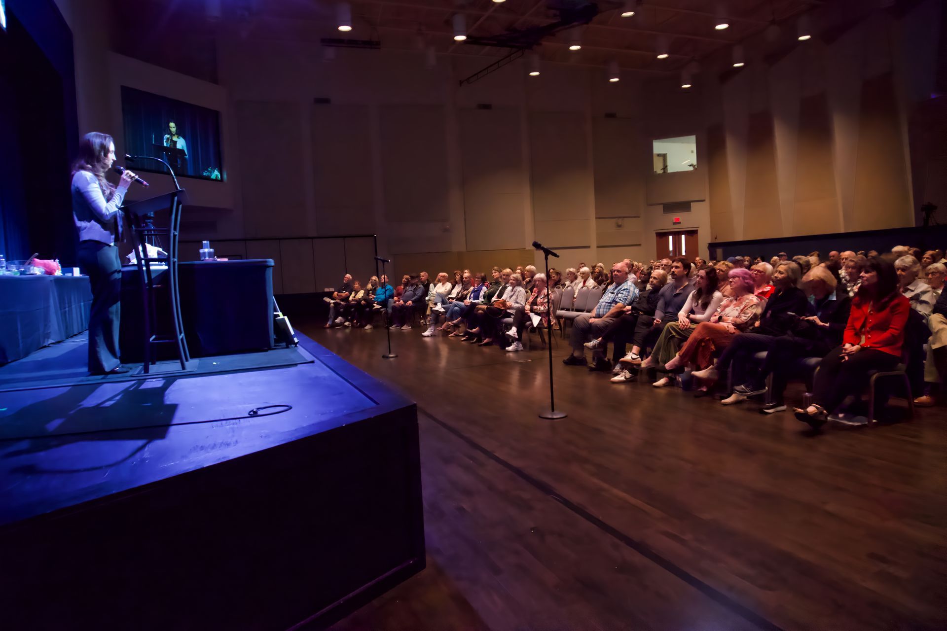 A woman is standing on a stage in front of a crowd.