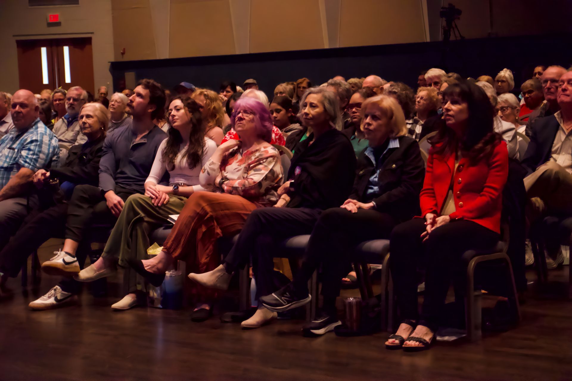 A large group of people are sitting in chairs in an auditorium.