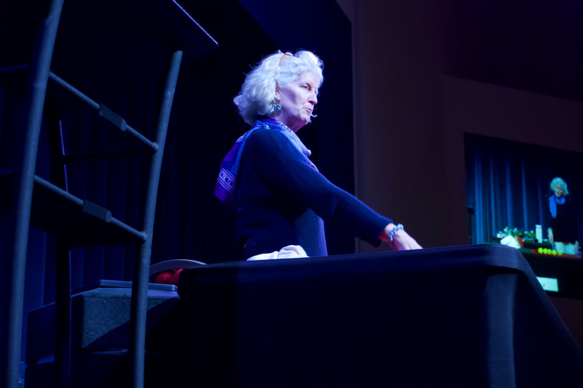 A woman is standing in front of a podium in a dark room.