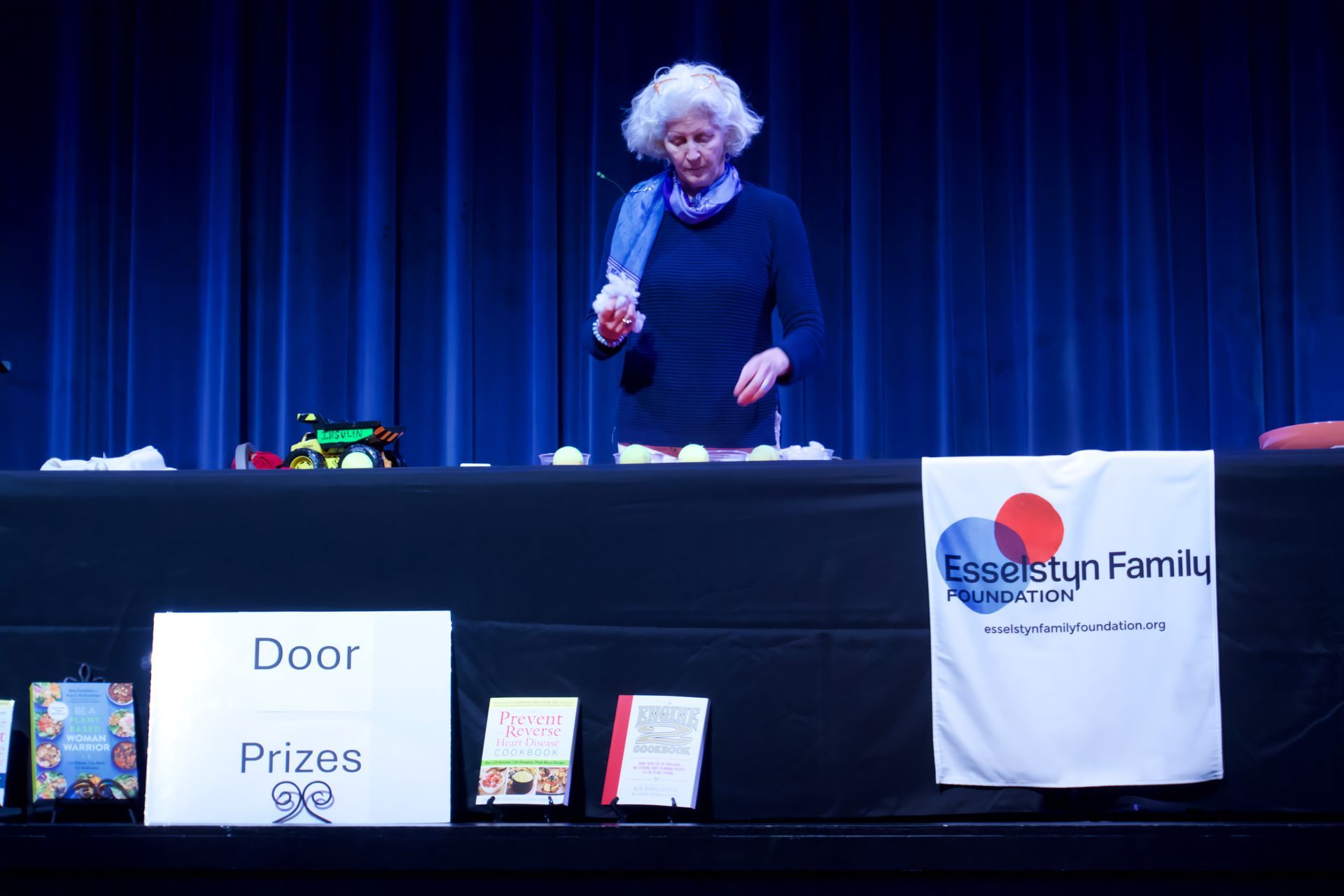 A woman stands behind a table with a sign that says door prizes